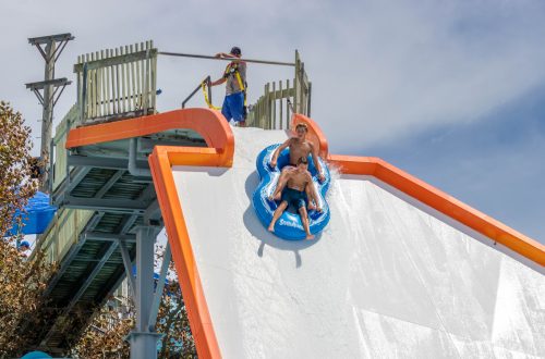 Two boys going down a raft on a huge water slide