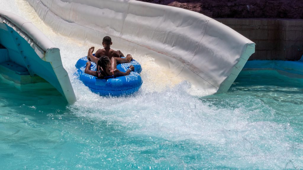 Large white slide with man in blue raft sliding down