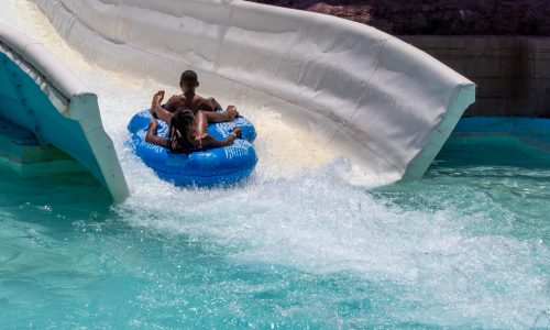 Large white slide with man in blue raft sliding down