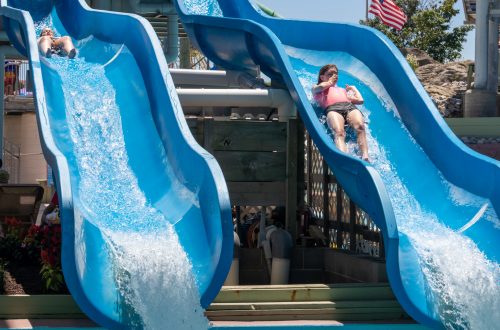 Woman holding her nose as she slides down blue water slides