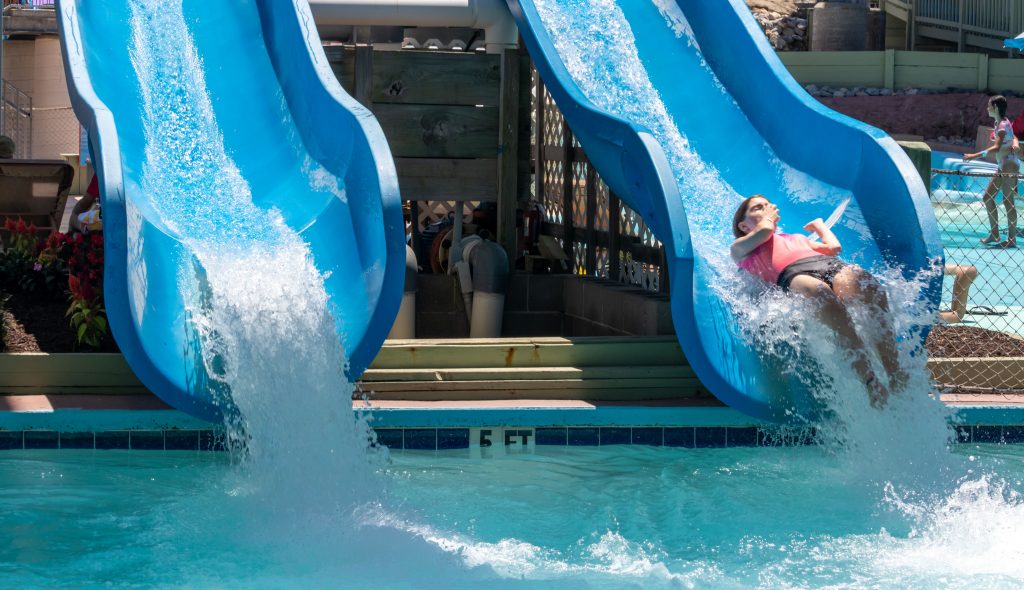Woman holding her nose as she is about to get dumped off the slide into the water