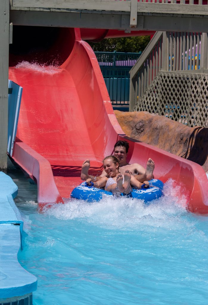 Man and woman on blue raft going down big red water slide